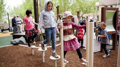 Children walking on stilt-like equipment in a play space